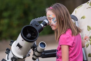 Little girl looking through telescope.